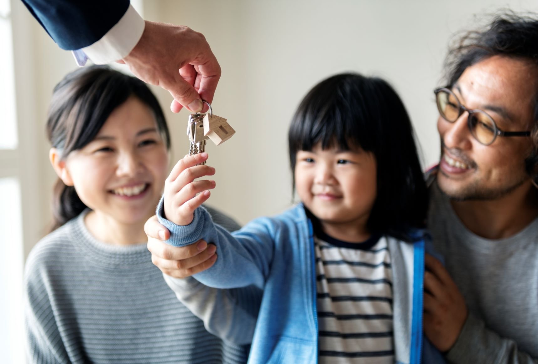 Asian family receiving the keys to their house | Oak Tree Finance Low Doc Home Loans landing page.