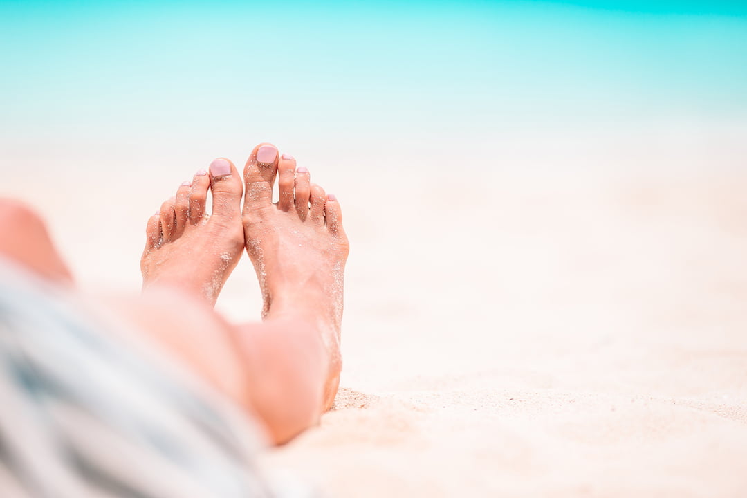 bare feet in the sand | Featured Image For Popular Holiday Spots to Invest In blog