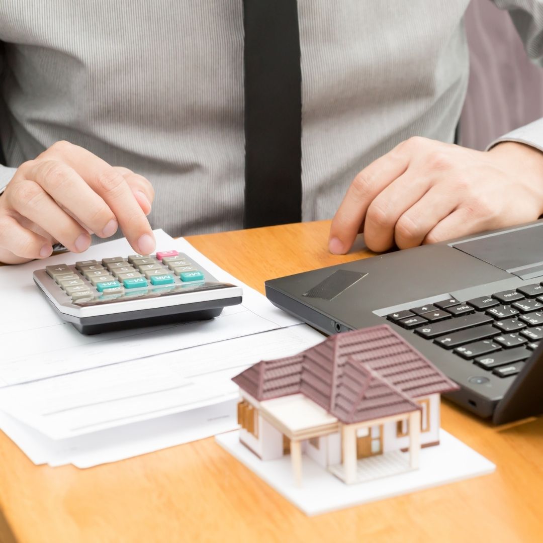 Mortgage broker using a calculator and laptop | Featured image for Mortgage Switching blog.